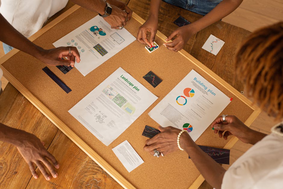 A diverse team collaborates on a workspace board with charts and plans.
